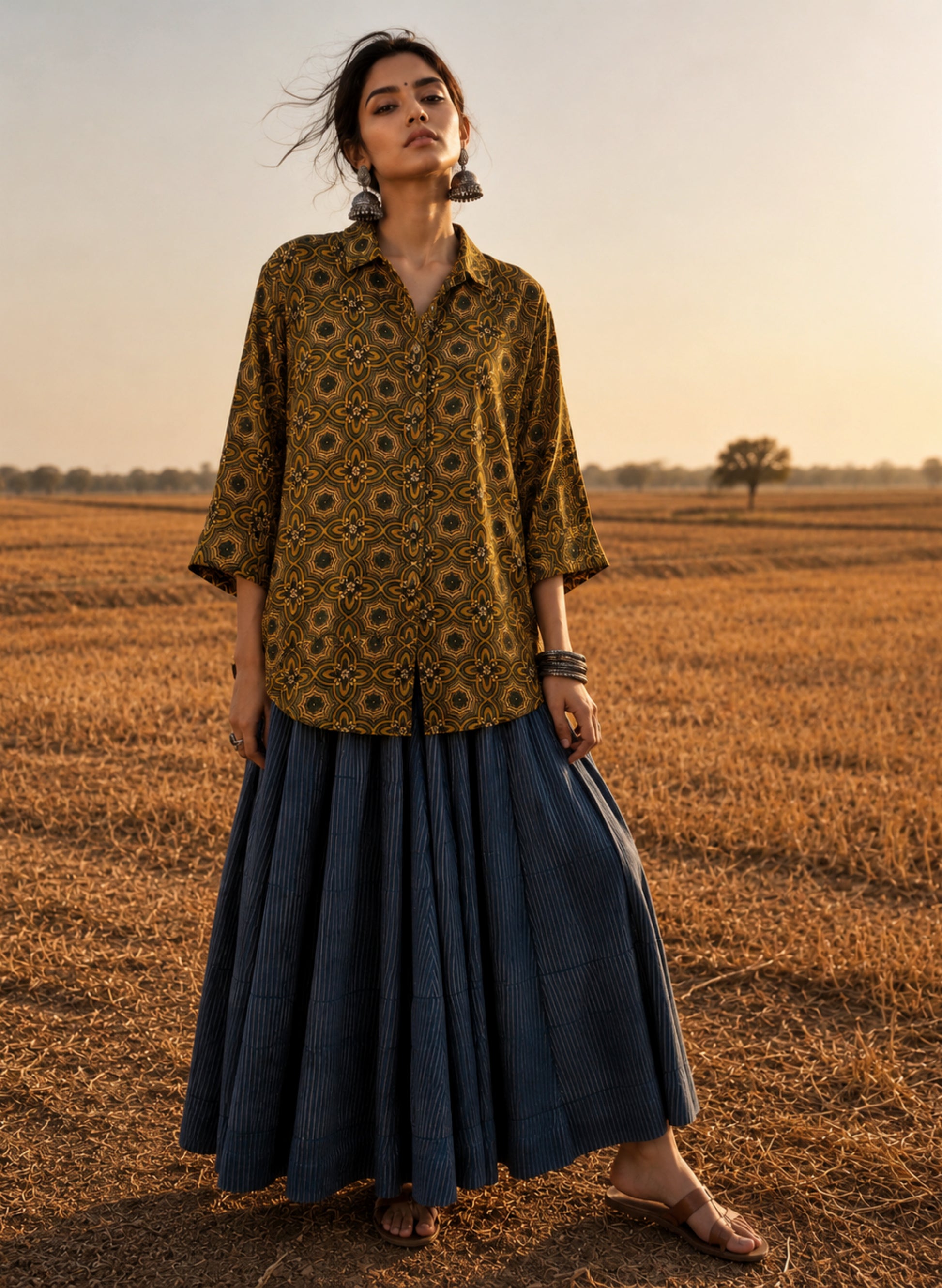 Turmeric dyed Ajrakh hand block printed modal silk oversized shirt for women in golden yellow with olive green and iron black geometric motifs.
