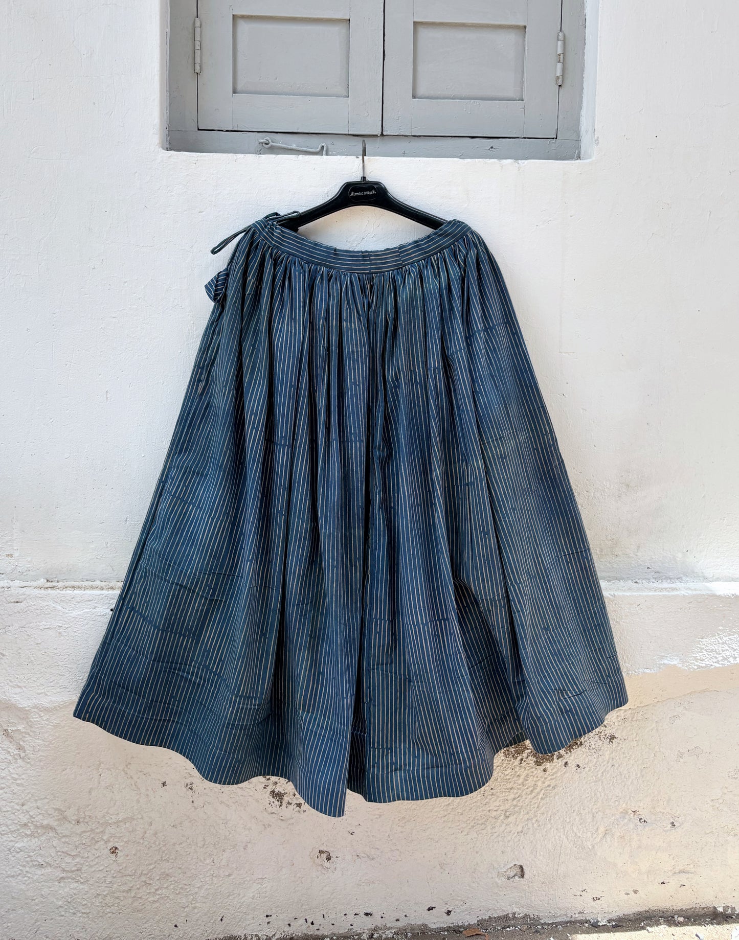Cotton indigo dyed Ajrakh hand block printed stripes skirt with gathered waistband, adjustable tie strings and concealed side zip in a flowing ankle-length silhouette.