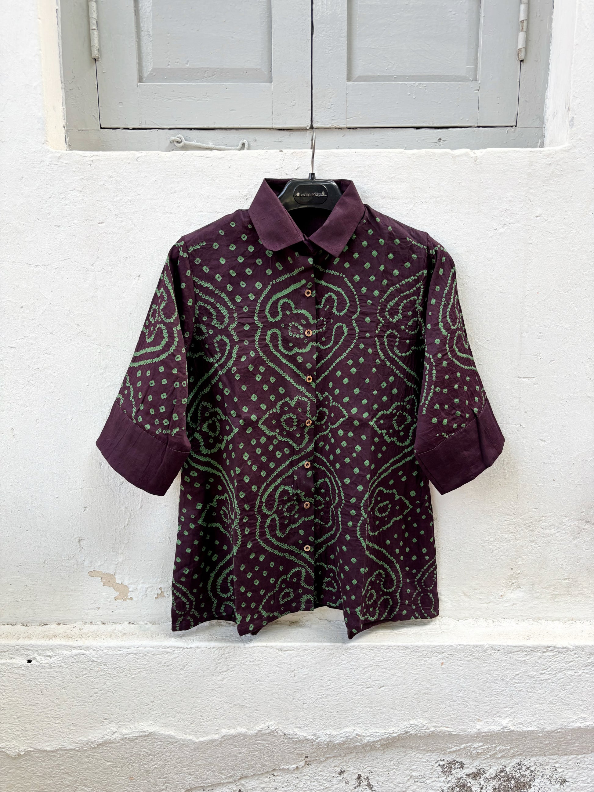 Jhankar Bandhani cotton shirt in deep jamun purple with sage green paisley motifs, classic shirt collar, folded sleeve cuffs, coconut shell buttons, and relaxed fit.