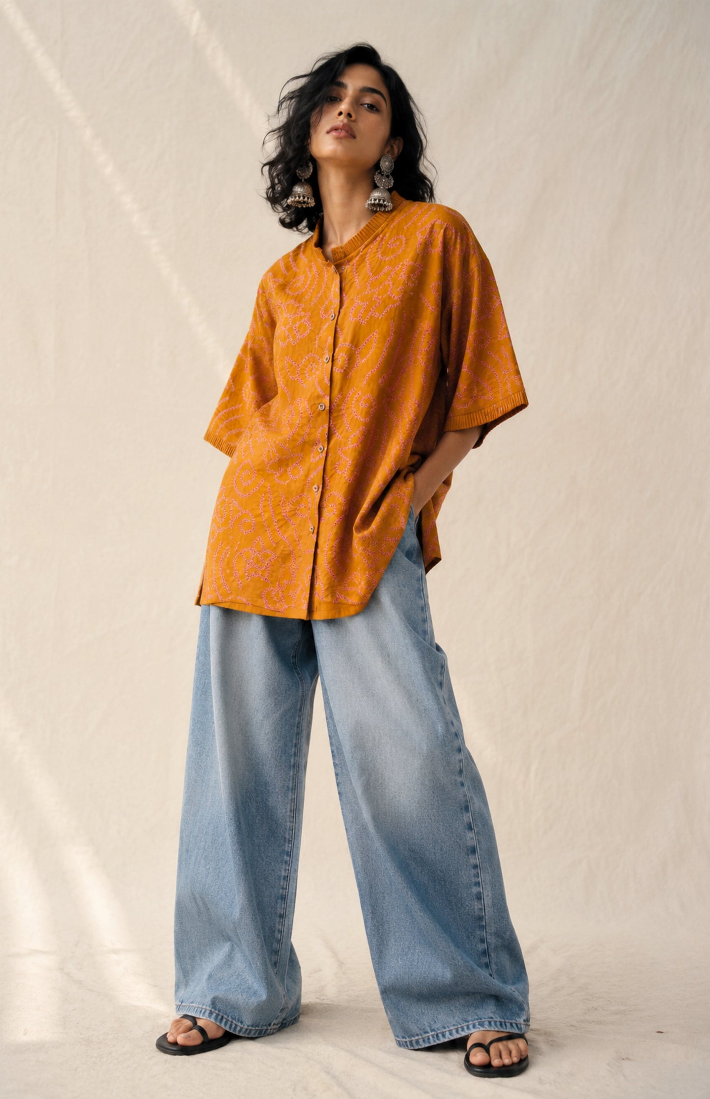 Hand tie-dyed Kesari ochre cotton Bandhani shirt with muted purple Jhankaar motifs, pleated neckline and relaxed fit.