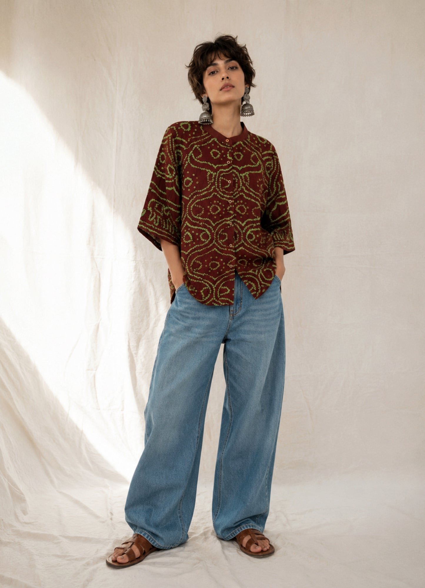 Deep mahogany brown cotton Jhankaar Bandhani shirt with vibrant parrot green motifs, handcrafted elephant details on the sleeve hems, soft mandarin collar and relaxed fit.