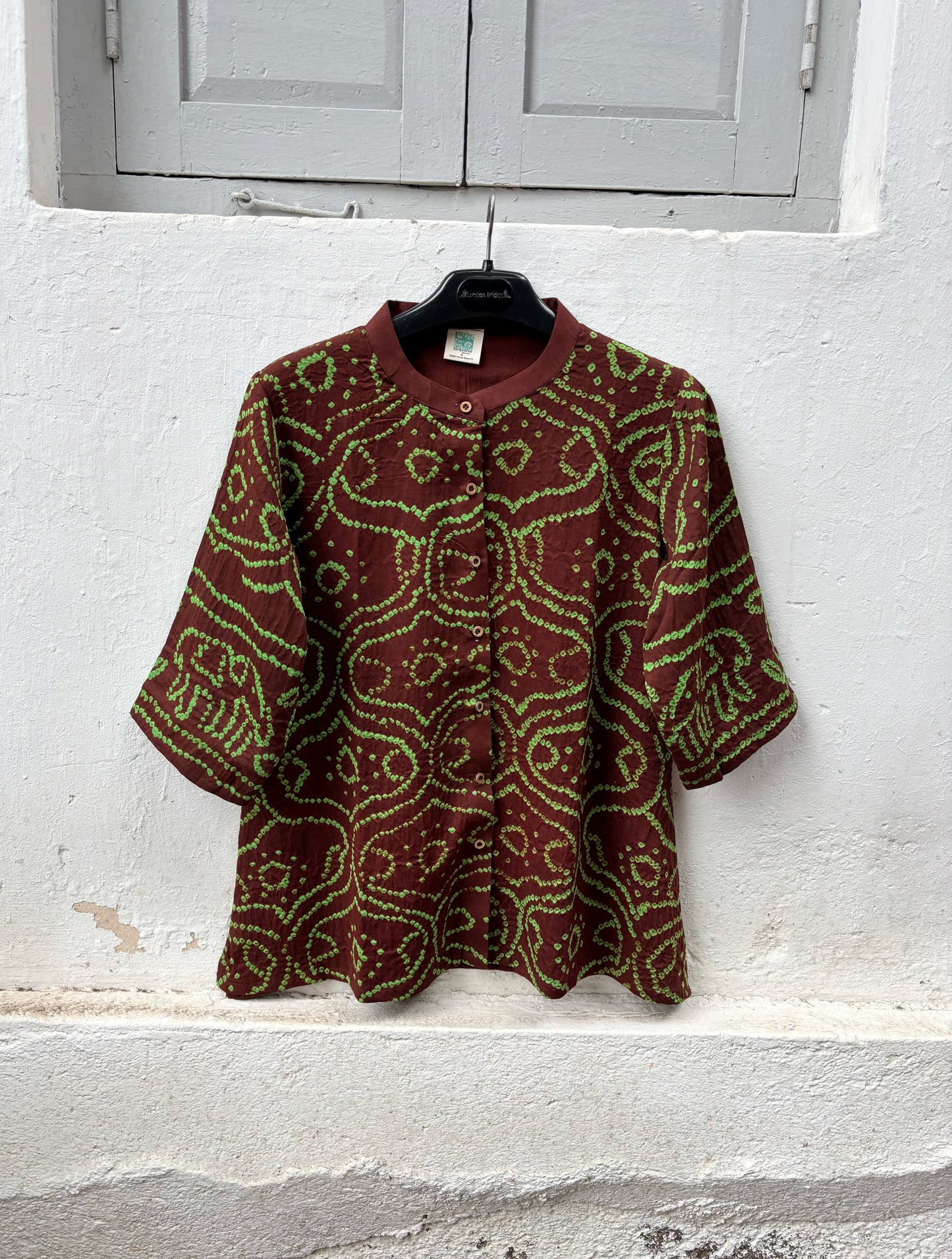 Deep mahogany brown cotton Jhankaar Bandhani shirt with vibrant parrot green motifs, handcrafted elephant details on the sleeve hems, soft mandarin collar and relaxed fit.