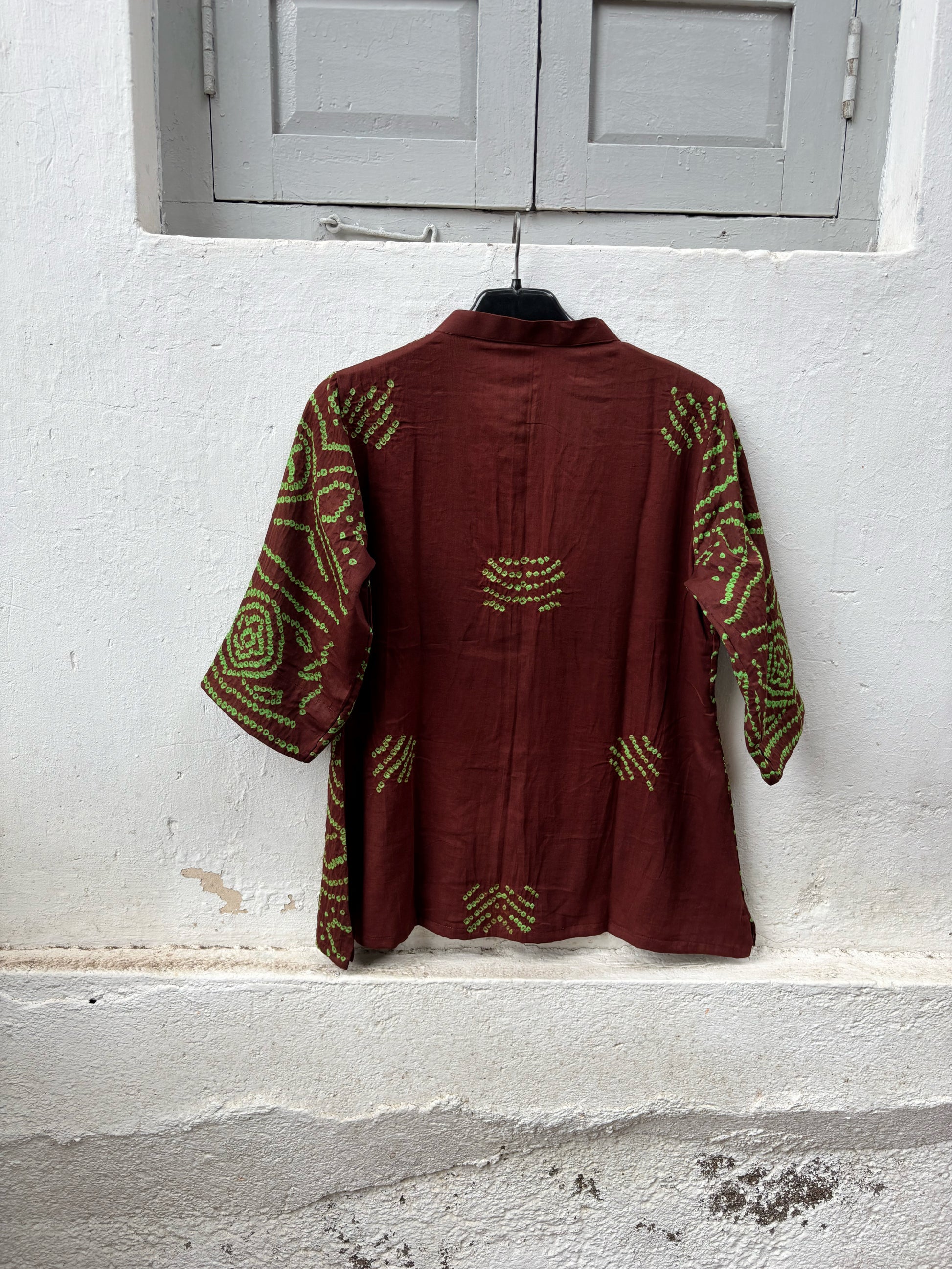 Deep mahogany brown cotton Jhankaar Bandhani shirt with vibrant parrot green motifs, handcrafted elephant details on the sleeve hems, soft mandarin collar and relaxed fit.