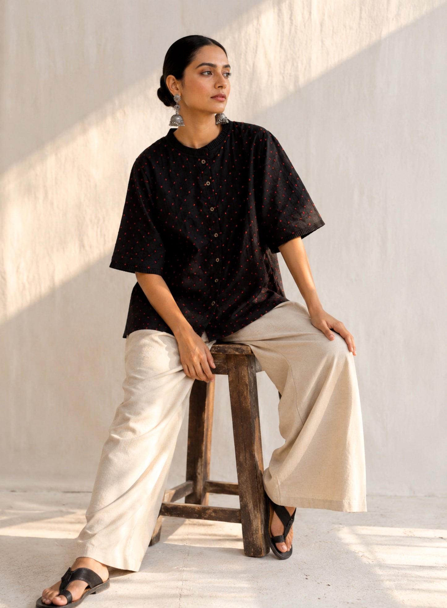 Black cotton satin shirt with burnt orange and deep red hand-tied thread knot detailing, pleated neckline and plain black back.