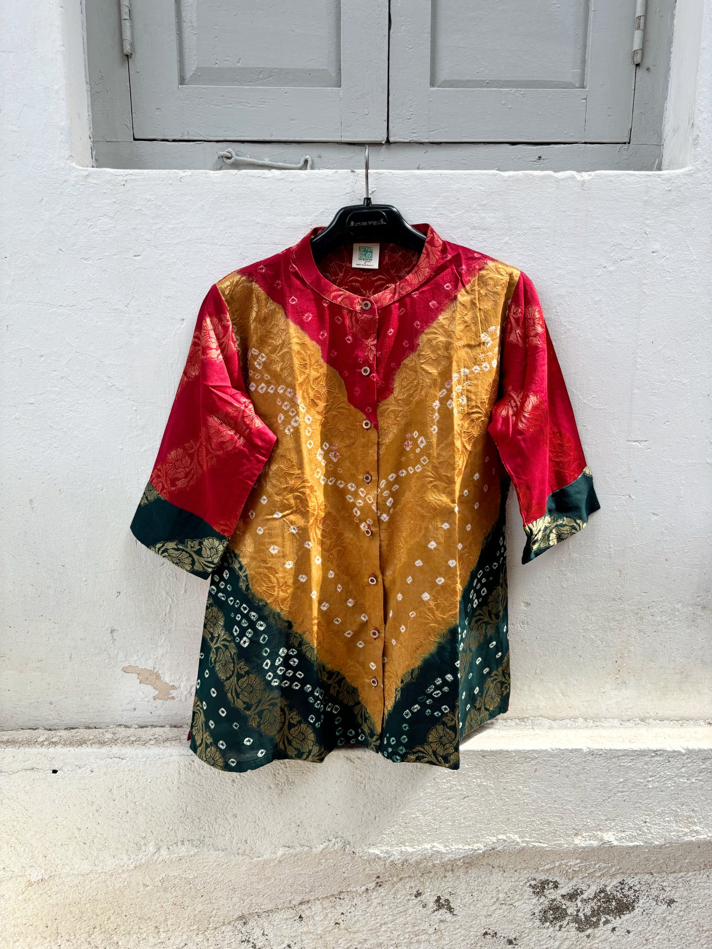 Handcrafted Bandhani festive cotton shirt in Crimson Red, Antique Mustard and Forest Green with antique gold woven floral motifs, mandarin band collar, front button closure, relaxed fit and three-quarter sleeves.

