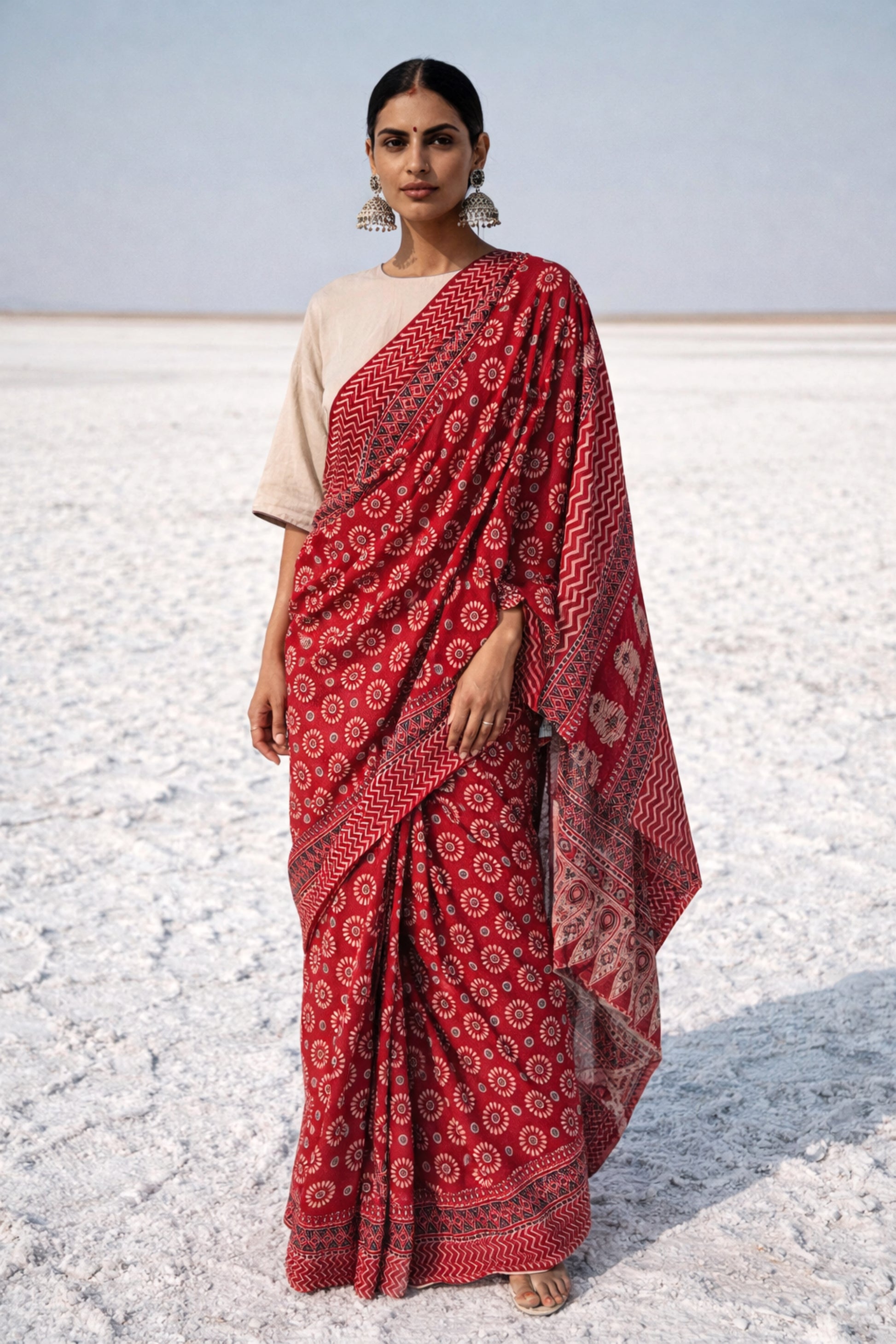 Madder dyed Ajrakh hand block printed cotton saree featuring circular motifs and geometric borders in deep red natural dye.