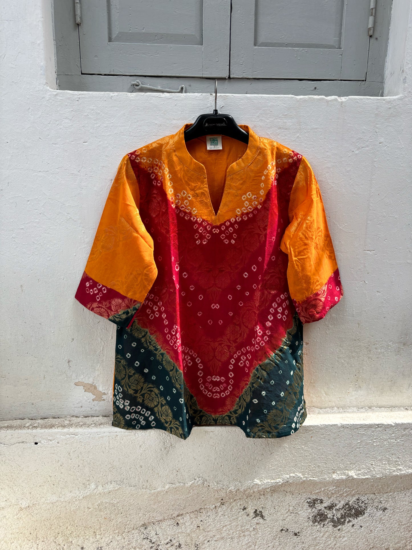 Handcrafted Bandhani festive cotton top in Saffron Yellow, Crimson Red and Deep Teal with antique gold woven floral motifs, mandarin V-neck, relaxed fit and three-quarter sleeves.
