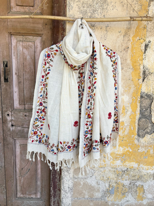 Handspun cotton dupatta in warm ivory shade with detailed floral vine hand embroidery in red, blue, mustard, and green tones. Lightweight, breathable handcrafted dupatta with tassel edges, named Latika.