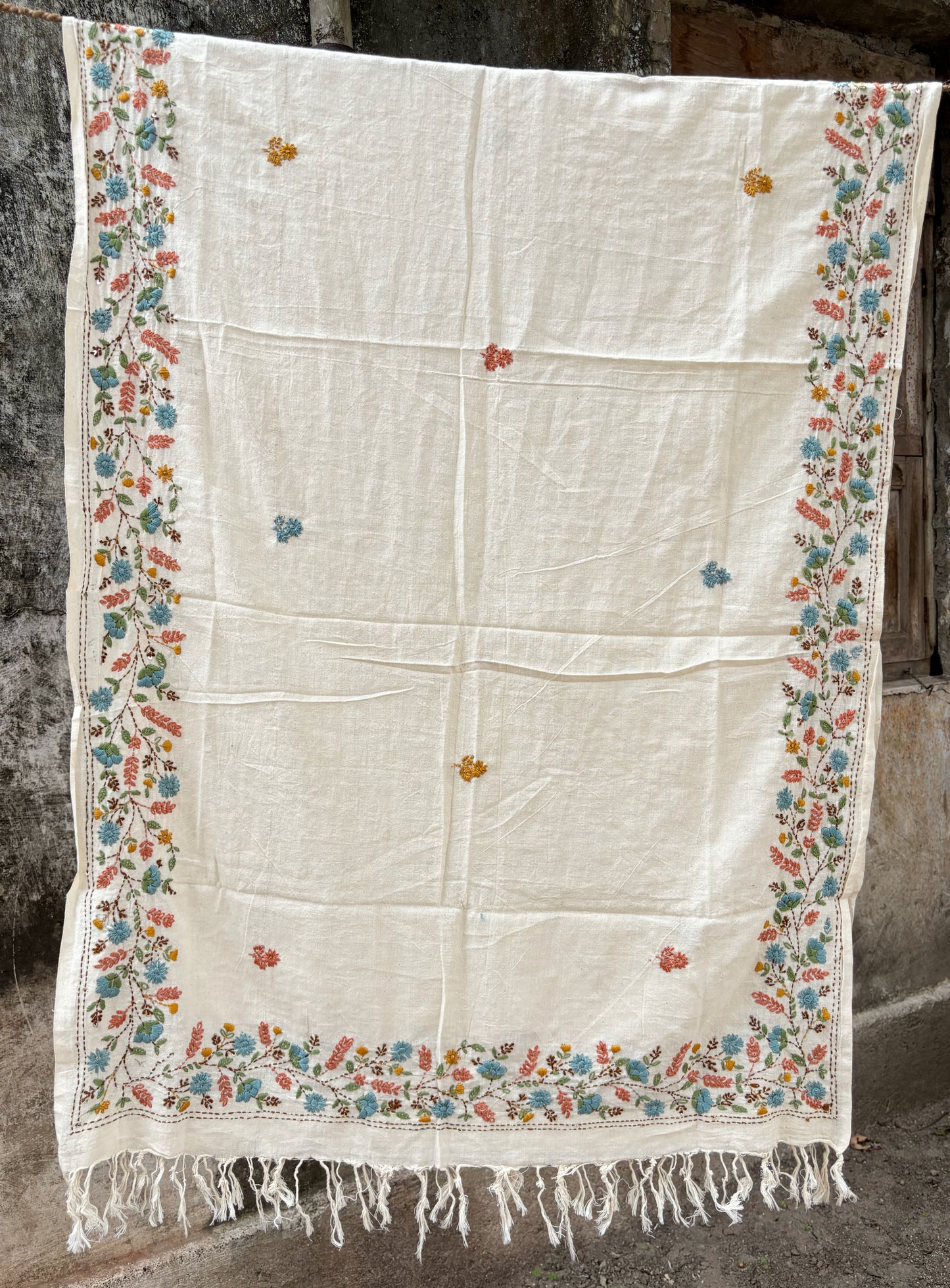 Maalti hand spun and handwoven off-white cotton dupatta with powder blue, coral, mustard, and olive floral embroidered borders, scattered floral butis, and handcrafted tassels.