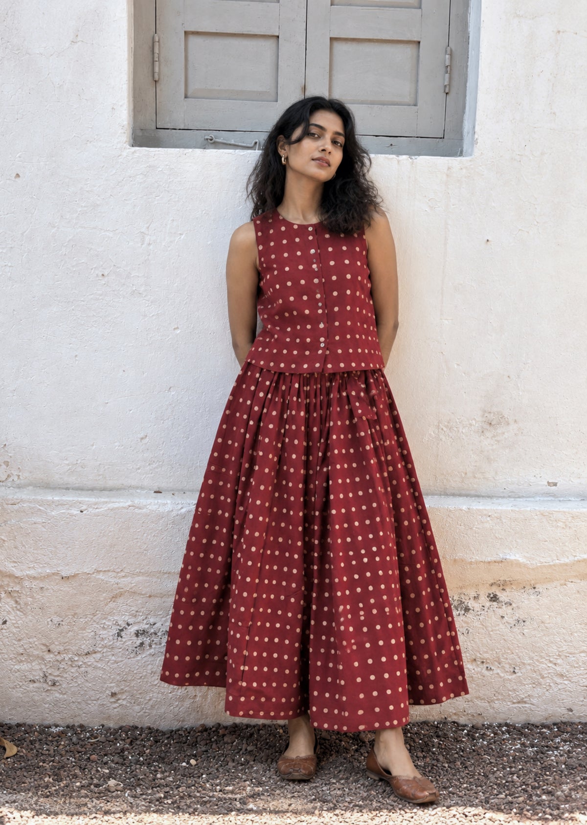 Madhu madder-red Ajrakh cotton co-ord set with a sleeveless cropped top and gathered skirt featuring beige hand block printed dots.