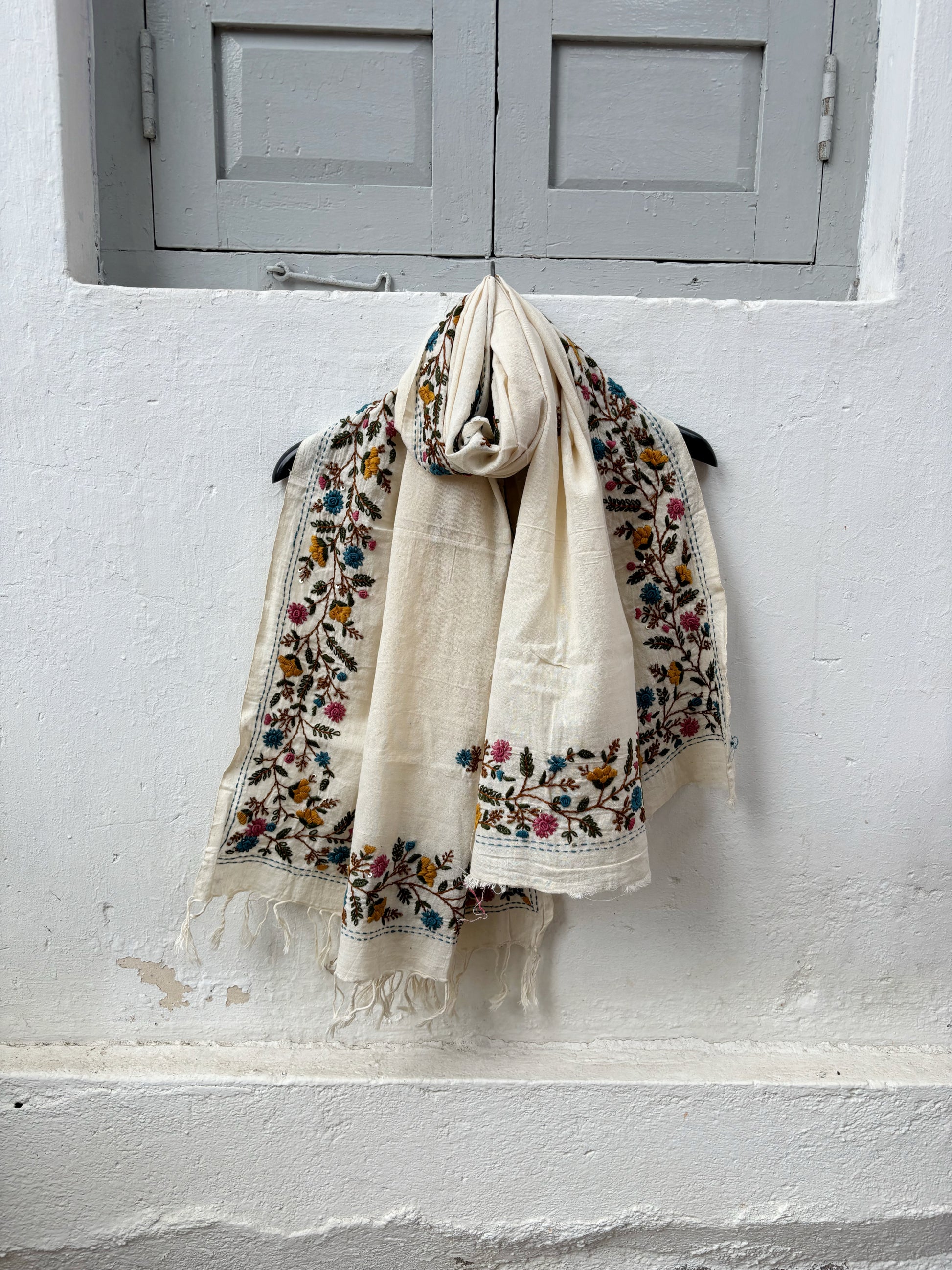 Madhumalti hand spun and handwoven off-white cotton dupatta with multicolour floral embroidered borders, scattered embroidered butis, and handcrafted tassels.