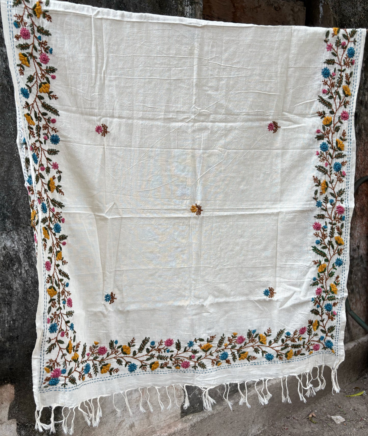 Madhumalti hand spun and handwoven off-white cotton dupatta with multicolour floral embroidered borders, scattered embroidered butis, and handcrafted tassels.