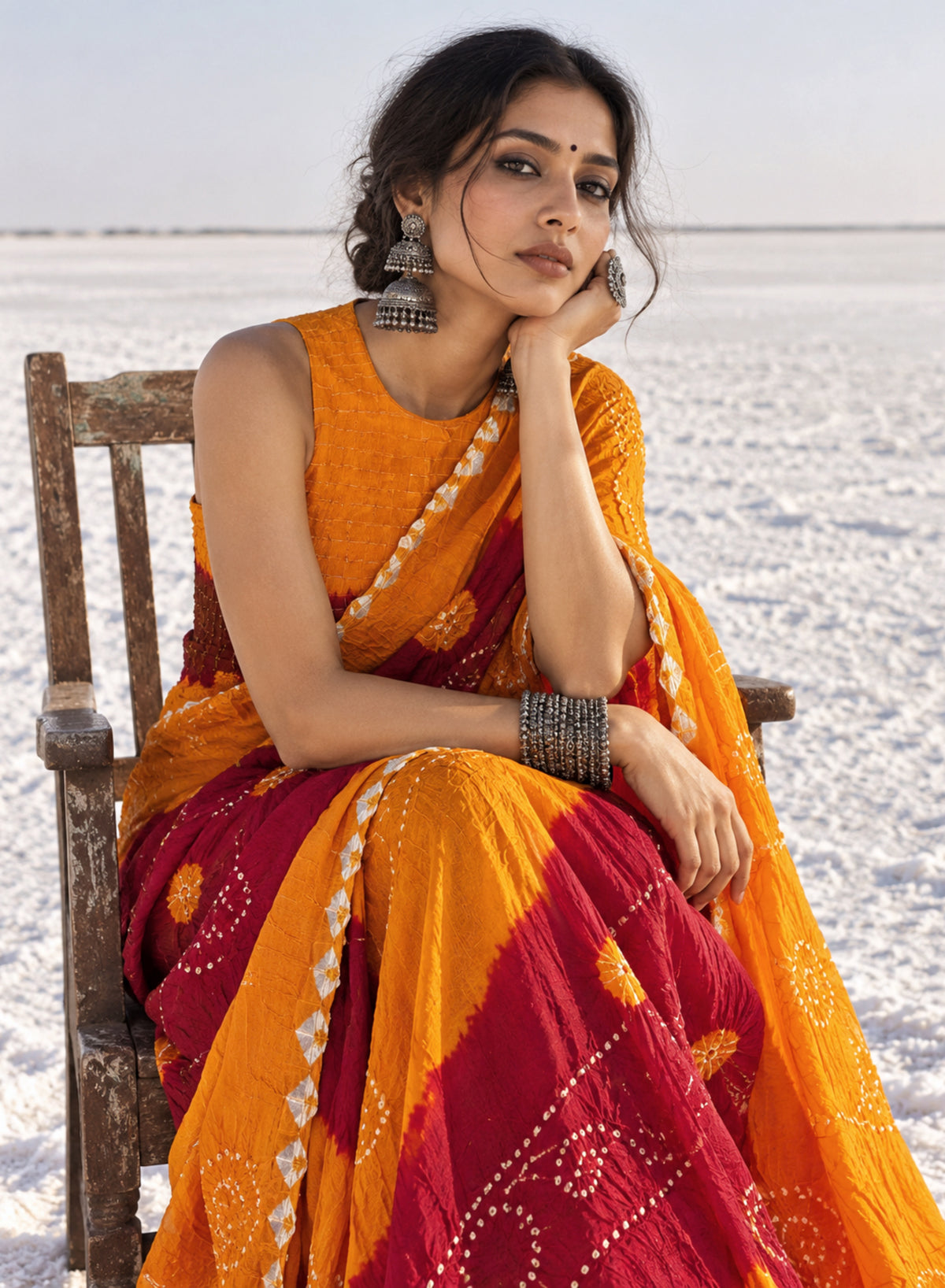 Marigold orange and deep maroon hand tie-dyed Bandhani cotton saree with floral and geometric motifs
