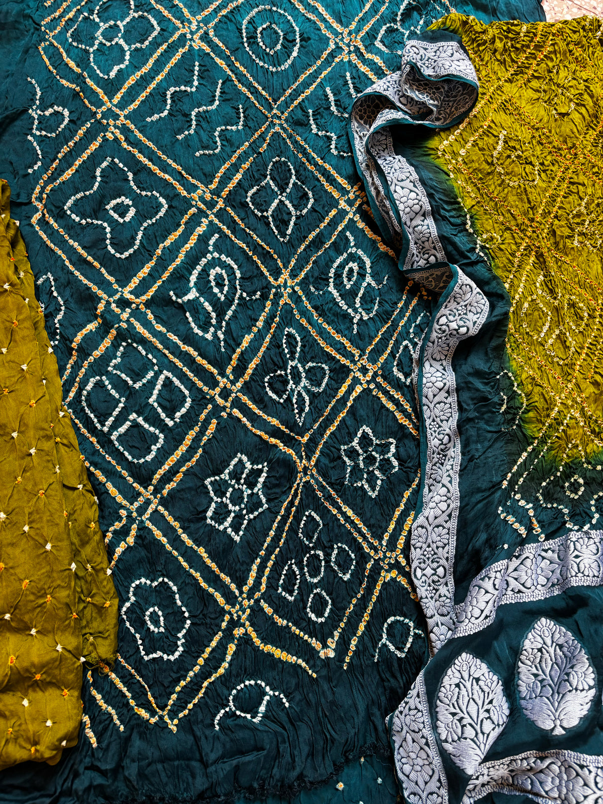 Three-piece modal silk Bandhani unstitched suit set in deep teal and olive green with self-thread woven dupatta borders