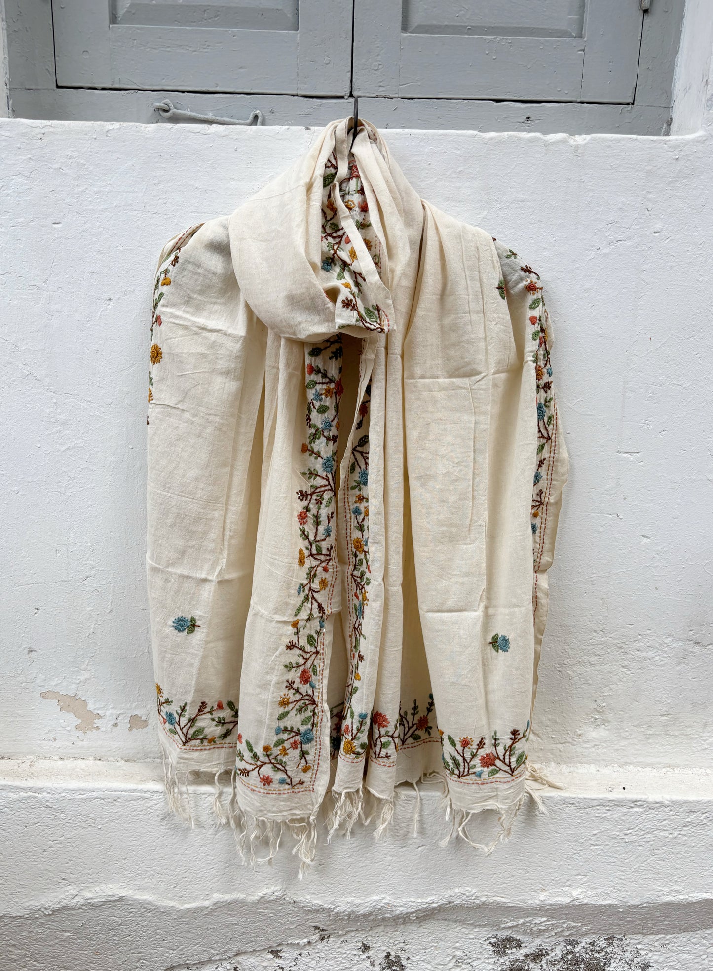 Mogra hand spun and handwoven off-white cotton dupatta with powder blue, coral, mustard, and olive floral embroidered borders, scattered floral butis, and handcrafted tassels.