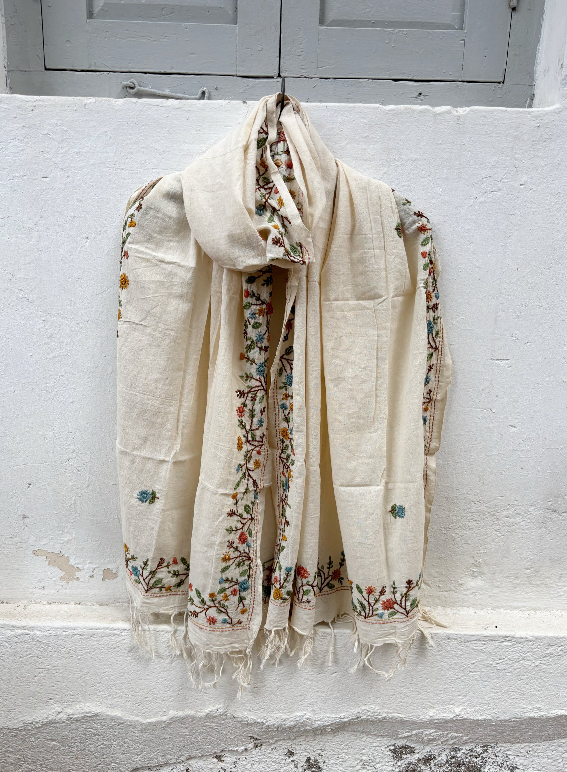 Mogra hand spun and handwoven off-white cotton dupatta with powder blue, coral, mustard, and olive floral embroidered borders, scattered floral butis, and handcrafted tassels.
