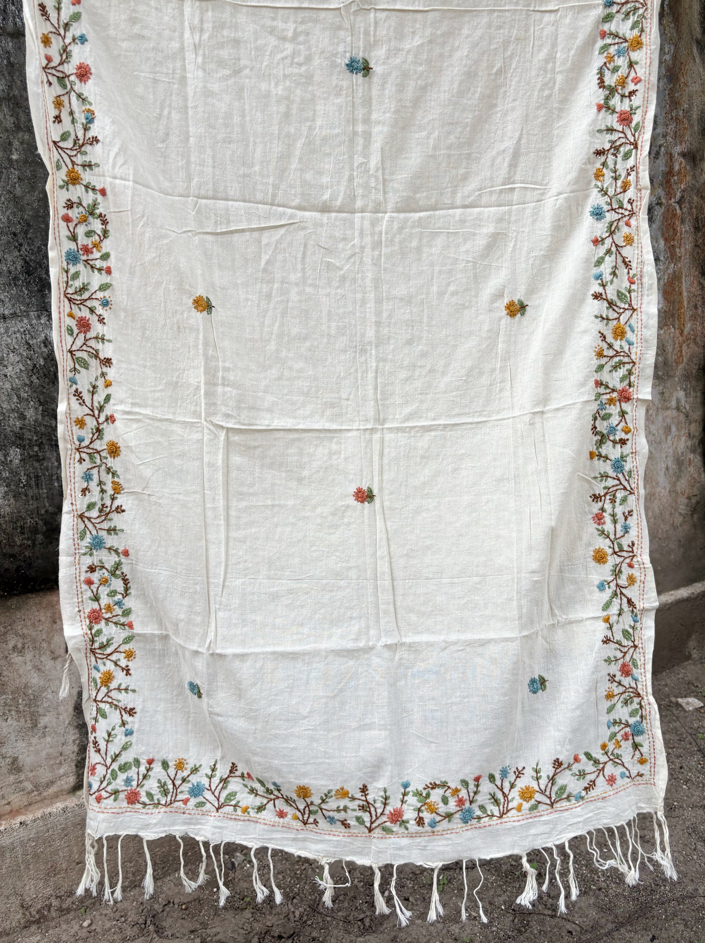 Mogra hand spun and handwoven off-white cotton dupatta with powder blue, coral, mustard, and olive floral embroidered borders, scattered floral butis, and handcrafted tassels.