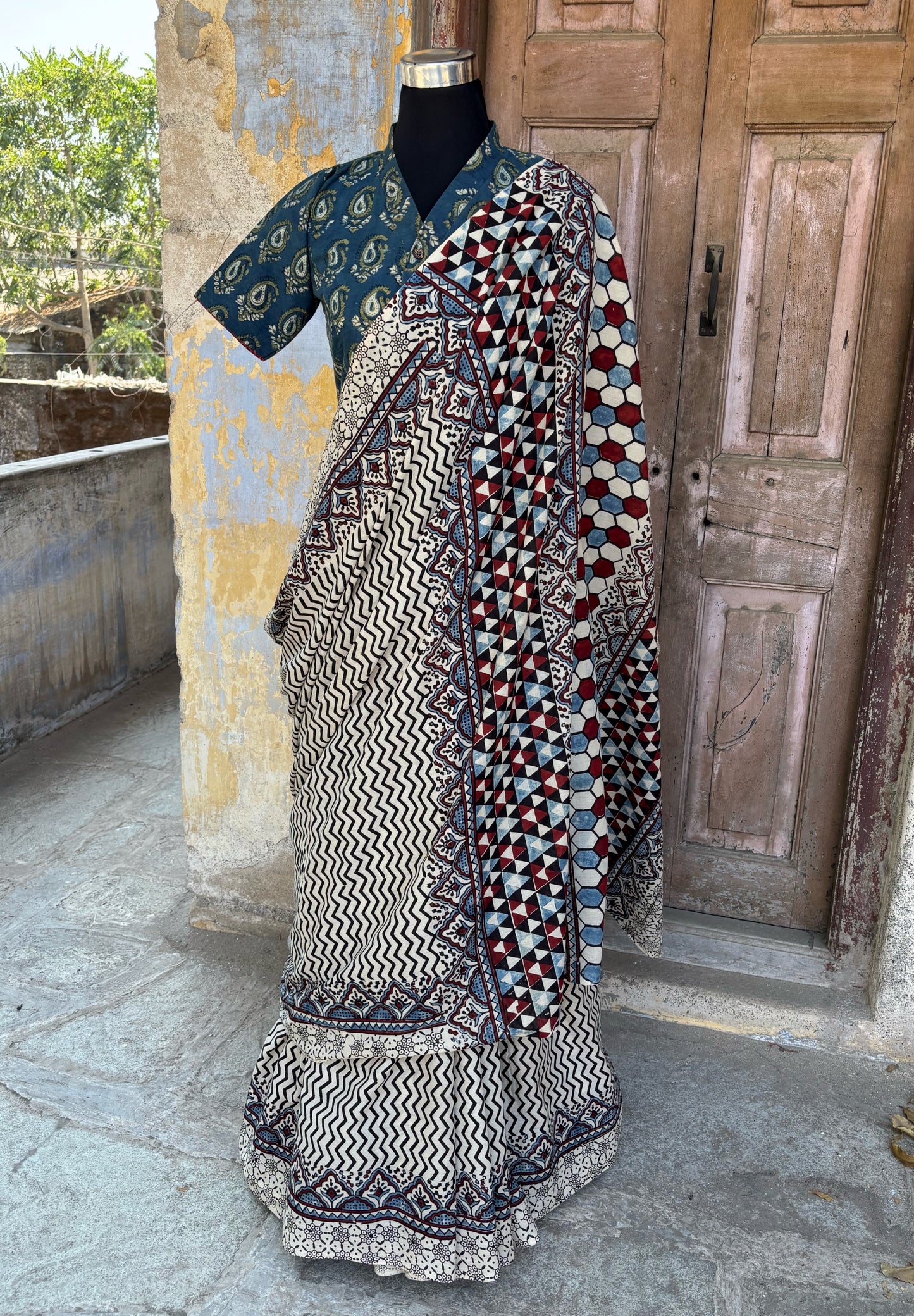 Myrobalan dyed pure cotton saree featuring traditional Ajrakh hand block prints with geometric motifs in indigo, madder red, and black tones, styled with a contrasting blouse.