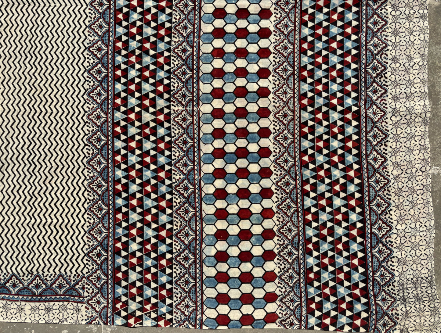 Myrobalan dyed pure cotton saree featuring traditional Ajrakh hand block prints with geometric motifs in indigo, madder red, and black tones, styled with a contrasting blouse.