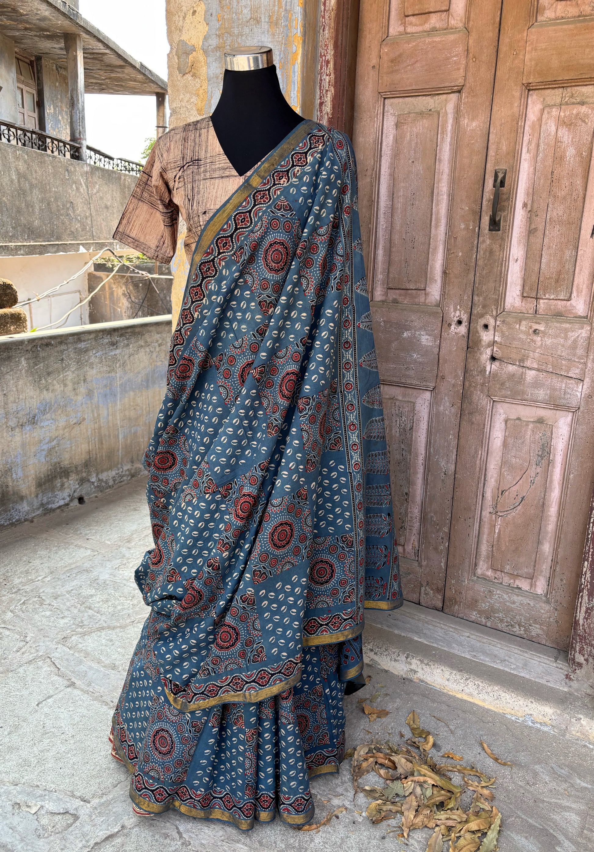 Indigo Ajrakh hand block printed cotton saree featuring traditional circular and geometric motifs with a thin border, paired with a madder dyed Ajrakh blouse piece.