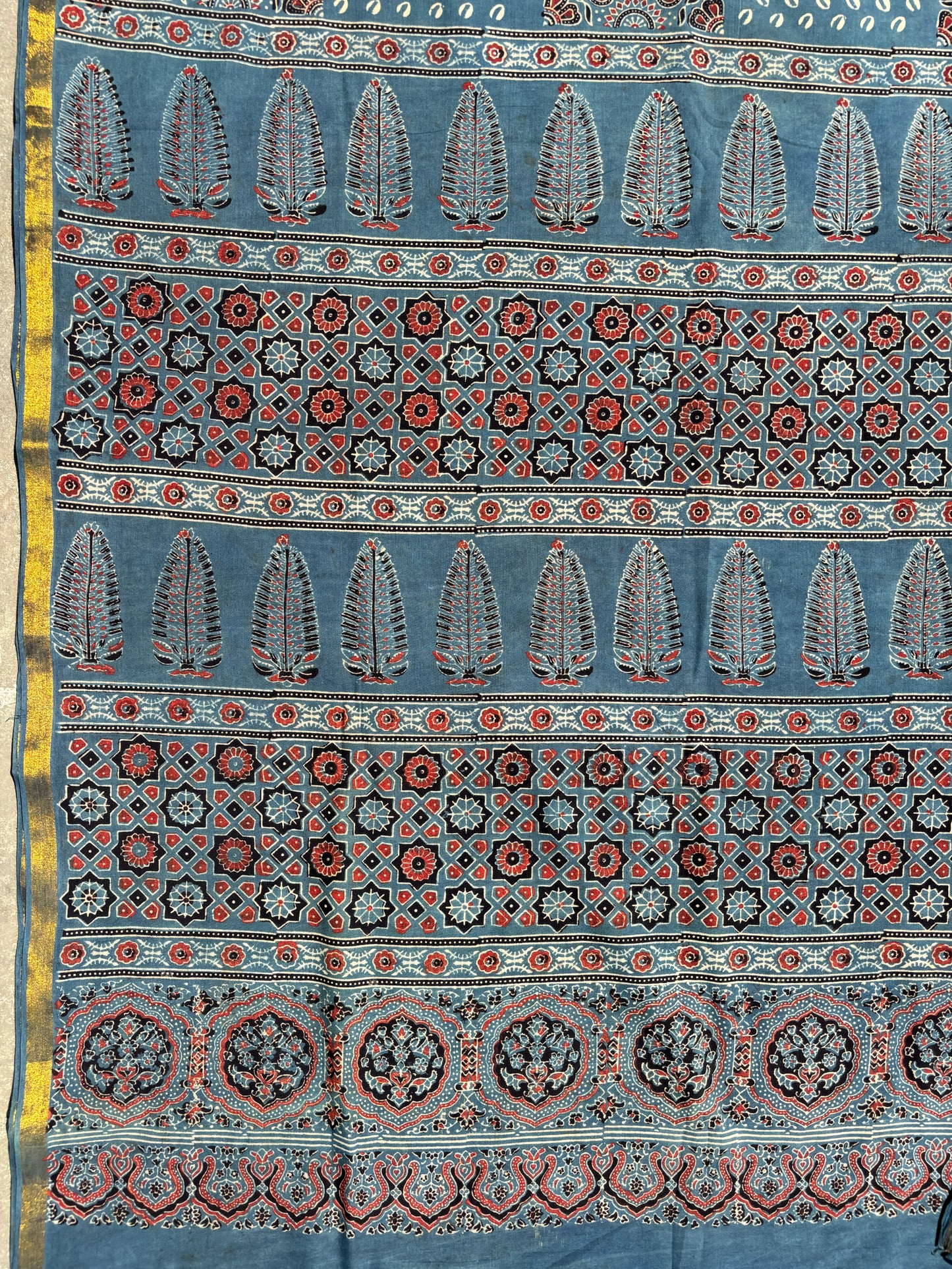 Indigo Ajrakh hand block printed cotton saree featuring traditional circular and geometric motifs with a thin border, paired with a madder dyed Ajrakh blouse piece.