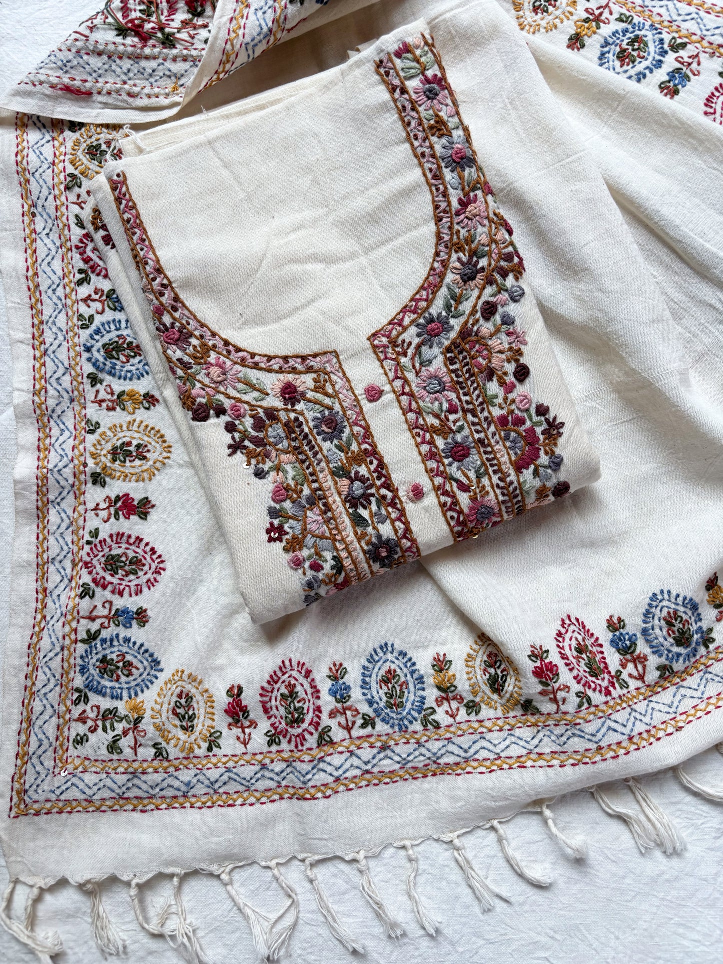 Handspun cotton unstitched kurta dupatta set with a finely hand embroidered floral yoke, small butti motifs on the kurta, and a matching hand embroidered dupatta with tassels in warm ivory tones.