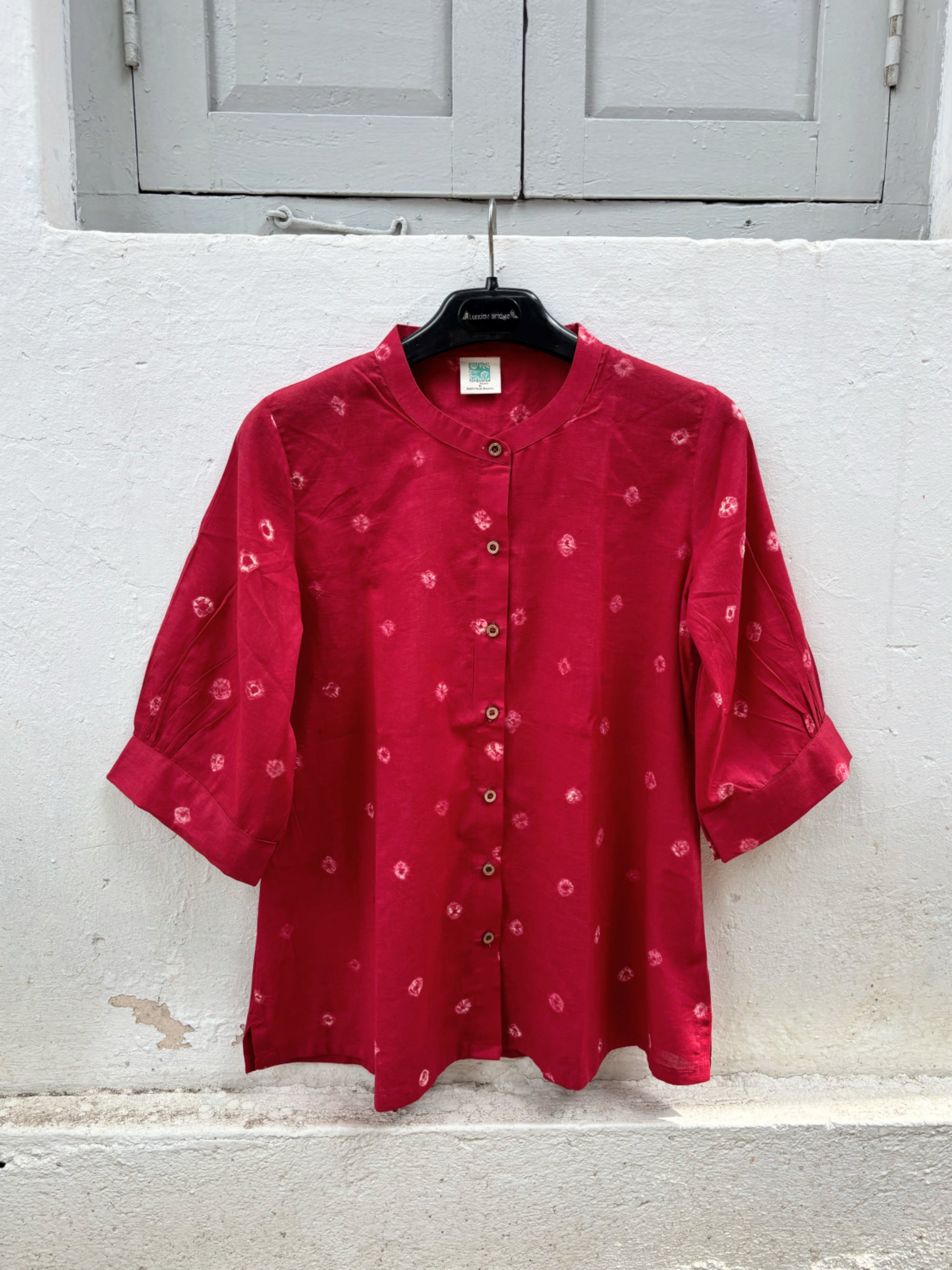 Women's ruby red cotton Bandhani shirt with pleated sleeves and wooden buttons.
