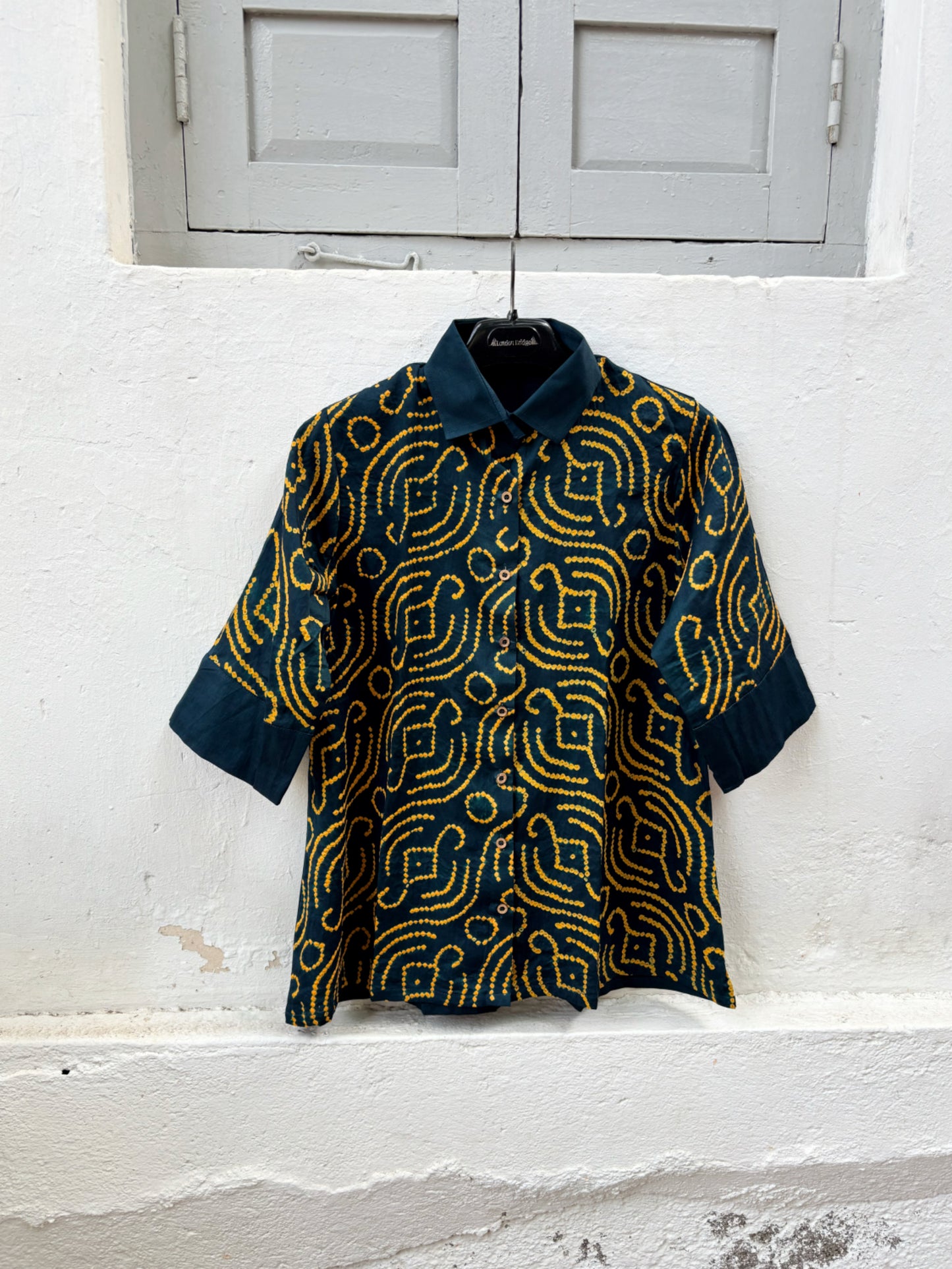 Jhankar Bandhani cotton shirt in midnight teal blue with saffron ochre motifs, classic shirt collar, folded sleeve cuffs, coconut shell buttons and relaxed fit.