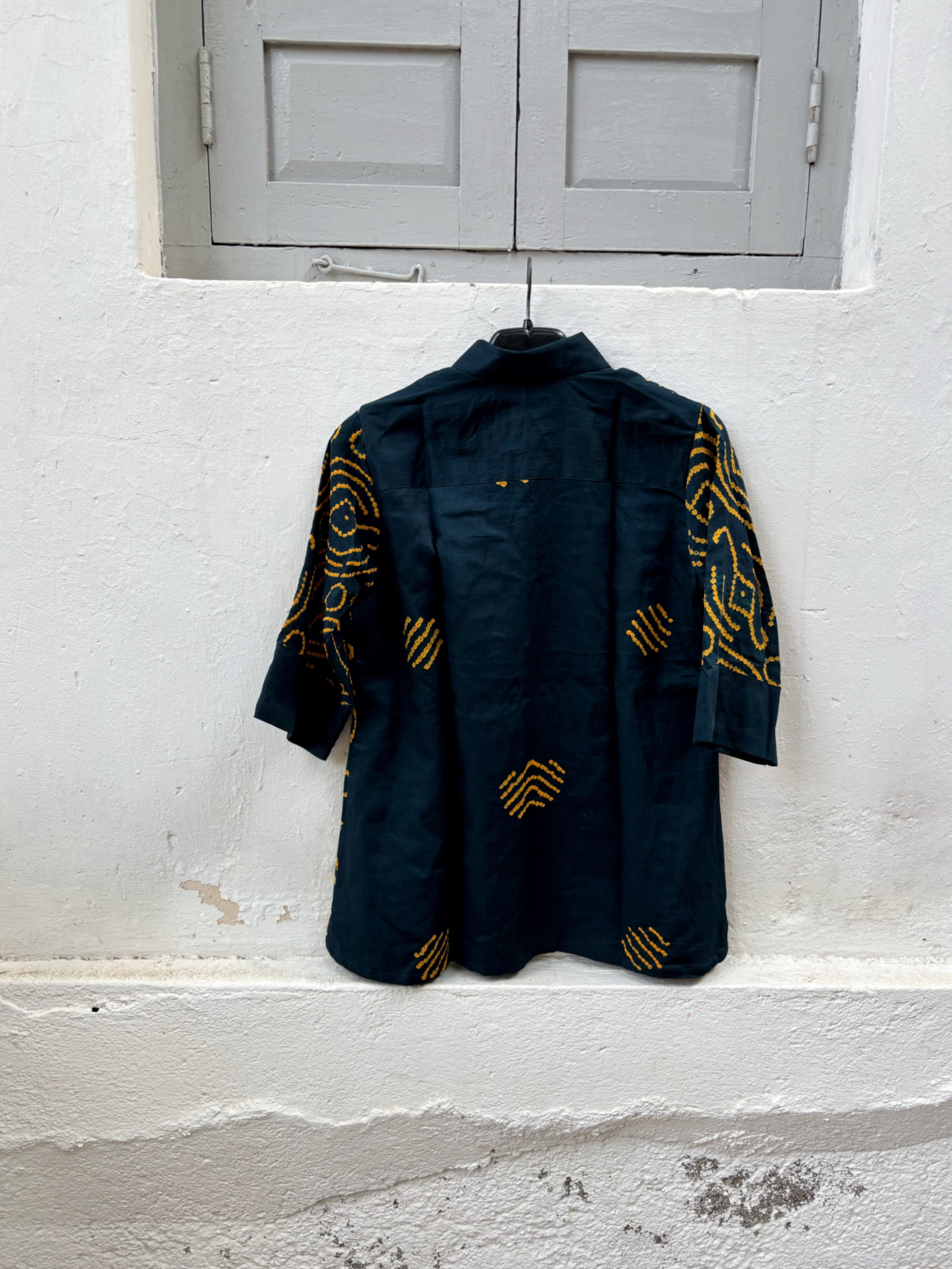 Jhankar Bandhani cotton shirt in midnight teal blue with saffron ochre motifs, classic shirt collar, folded sleeve cuffs, coconut shell buttons and relaxed fit.