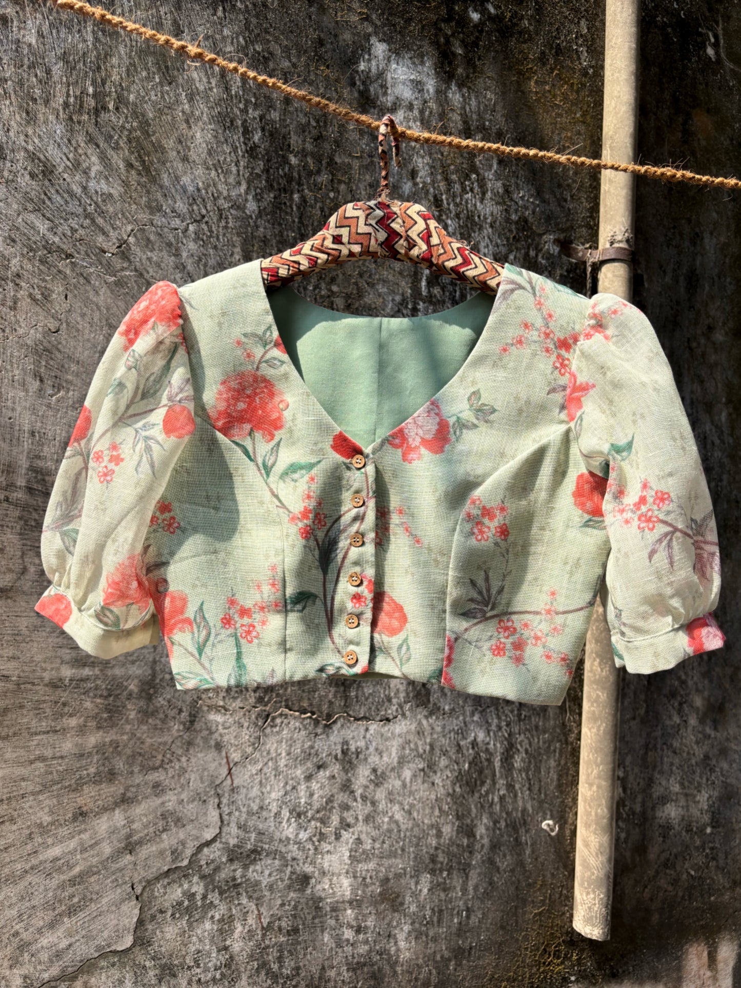 Slow-made sage green floral linen blouse with curved V-neck, front wooden buttons and subtle puff sleeves, fully lined and consciously crafted in India.