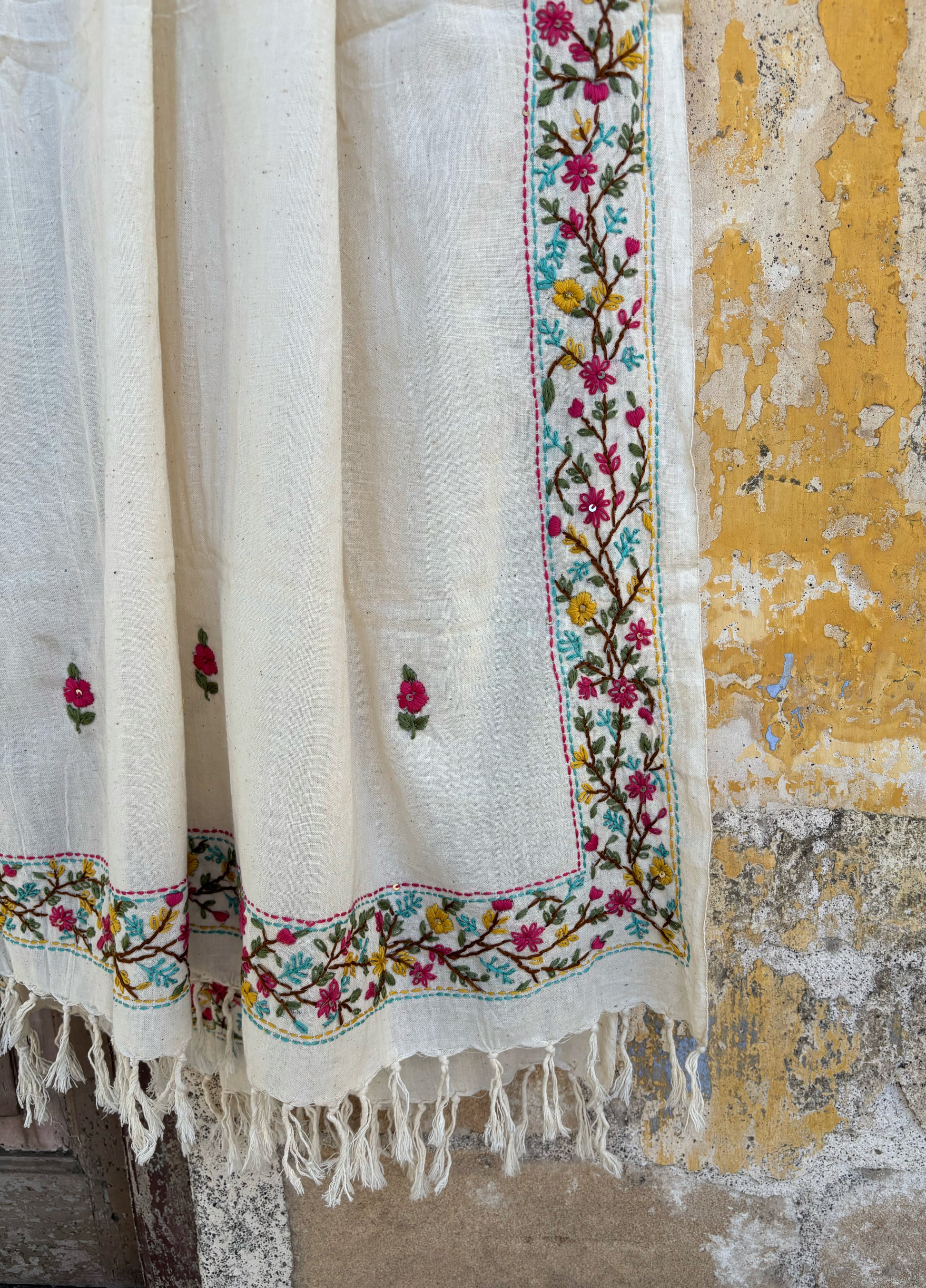 Handspun and handwoven cotton dupatta in warm ivory featuring delicate floral vine hand embroidery along the borders with small butti motifs and tassel edges.